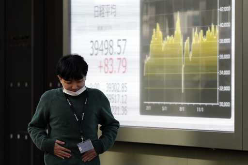 A person walks in front of an electronic stock board showing Japan's Nikkei index at a securities f…