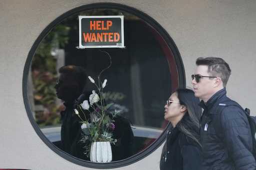 Pedestrians walk past a help wanted sign posted on the door of a restaurant in San Francisco, Tuesd…