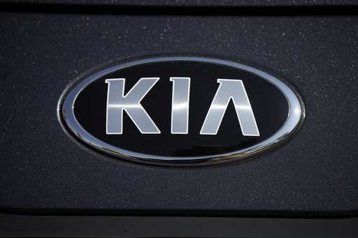 The company logo shines off the hood of a 2021 K5 sedan on display in the Kia exhibit at the Denver…