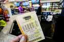 A Mega Millions ticket is seen as a person makes a purchase inside a convenience store, August 7, 2…