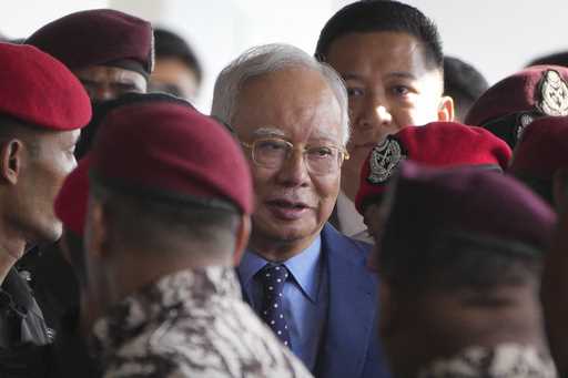 Malaysian former Prime Minister Najib Razak, center, is escorted by prison officers on his arrival …