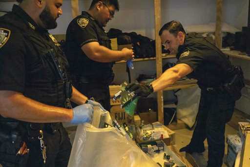 New York Police officers collect seized merchandise at an illegal cannabis shop during an enforceme…