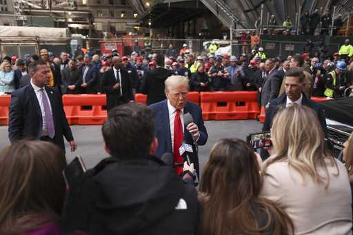 Former President Donald Trump speaks members of the media while visiting with construction workers …