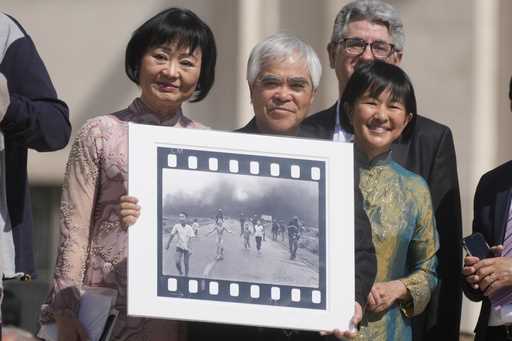 Pulitzer Prize-winning photographer Nick Ut, center, flanked by Kim Phuc, left, holds the "Napalm G…