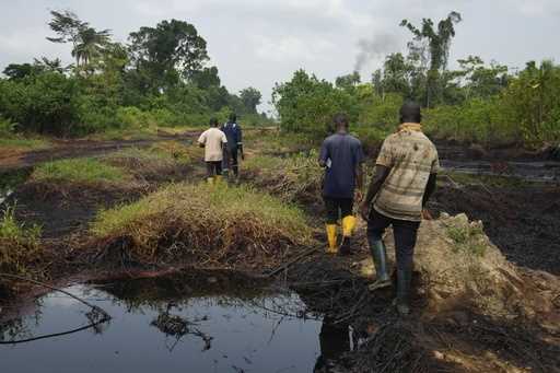 People walk amid an oil spill in the Niger Delta in village of Ogboinbiri, Nigeria, December 11, 20…