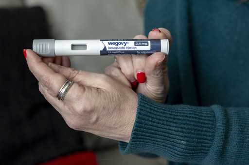 Donna Cooper holds up a dosage of Wegovy, a drug used for weight loss, at her home, March 1, 2024, …