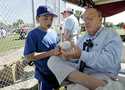 Former Major League Baseball Commissioner Fay Vincent signs an autograph for Louis Carrons, 12, of …