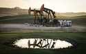 Pumpjacks draw out oil and gas from well heads as wildfire smoke hangs in the air near Calgary, Alb…