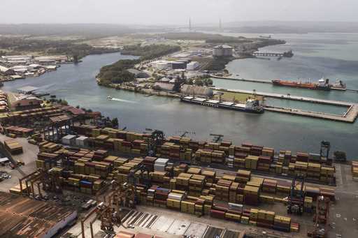 Cargo containers sit stacked as cranes load and unload containers from cargo ships at the Cristobal…