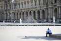 A lone man sit in the shadow in the courtyard of the Louvre museum, which is outside the security p…