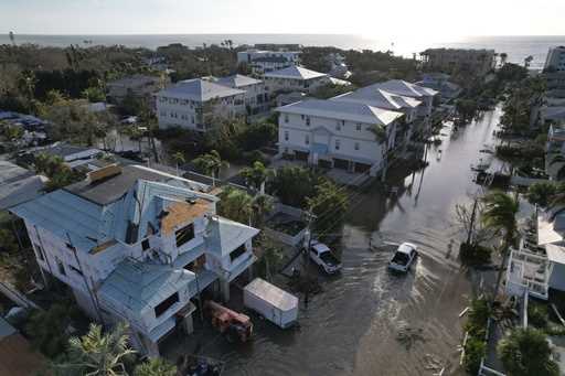 A truck drives down a flooded street in Siesta Key, Fla