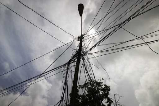 A utility pole with loose cables towers over a home in Loiza, Puerto Rico, Sept