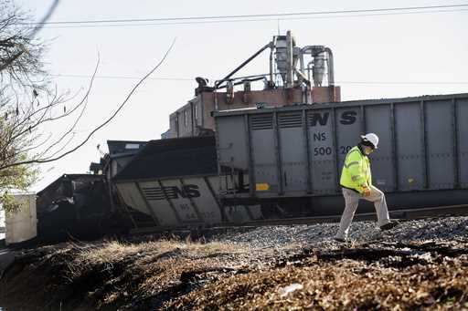 A Norfolk Southern worker walks next to the scene of a multi-car coal train derailment near Suffolk…