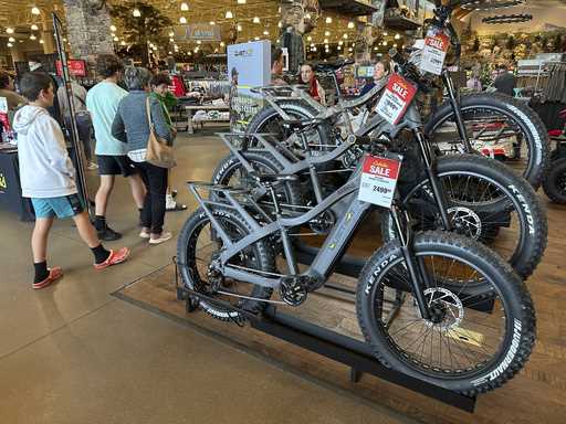 Shoppers pass by electric bicycles on display in a Cabela's sporting goods store Sunday, December 8…