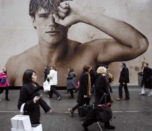 In this photo made December 9, 2009, shoppers walk past a billboard for an Abercrombie & Fitch stor…