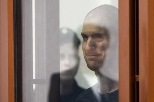 Wall Street Journal reporter Evan Gershkovich stands listening to the verdict in a glass cage of a …