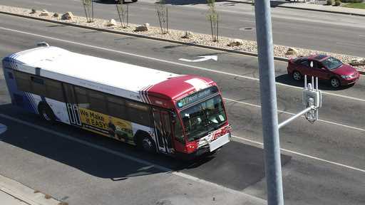 A commuter bus equipped with a radio transmitter approaches a connected traffic light on Redwood Ro…