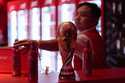 A bartender clears bottles of Budweiser beer from the bar near a replica of the FIFA World Cup trop…