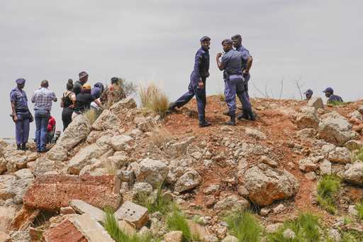 Police officers and volunteer rescuers stand by the opening of a reformed gold mineshaft where ille…