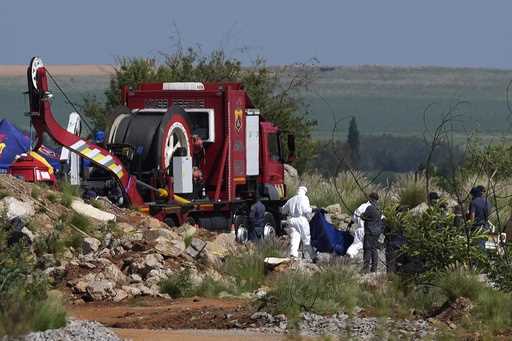 Police officers and private security personnel stand by the opening of a reformed gold mineshaft wh…