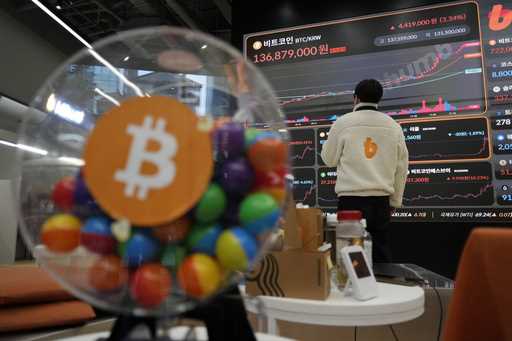 An employee watches an electronic signboard displaying the prices of Bitcoin and other cryptocurren…