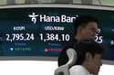 Currency traders watch monitors near the screen showing the Korea Composite Stock Price Index…
