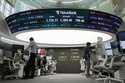 Currency traders work near the screen showing the Korea Composite Stock Price Index…