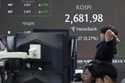 A currency trader stretches while working near a screen showing the Korea Composite Stock Price Ind…