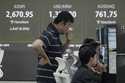 Currency traders watch monitors near a screen showing the Korea Composite Stock Price Index…