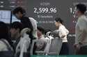 Currency traders work near a screen showing the Korea Composite Stock Price Index…