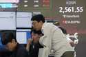 Currency traders watch monitors near a screen showing the Korea Composite Stock Price Index…