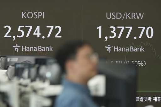 A currency trader walks by the screens showing the Korea Composite Stock Price Index…