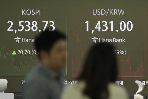 Currency traders talk near the screens showing the Korea Composite Stock Price Index…