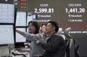 Currency traders watch monitors near a screen showing the Korea Composite Stock Price Index…