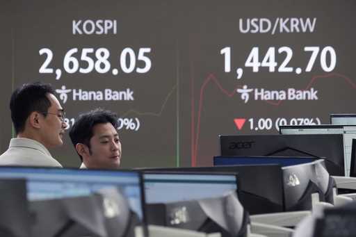 Currency traders watch monitors near a screen showing the Korea Composite Stock Price Index…