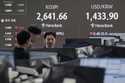 Currency traders watch monitors near a screen showing the Korea Composite Stock Price Index…