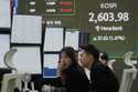 Currency traders watch monitors near a screen showing the Korea Composite Stock Price Index…