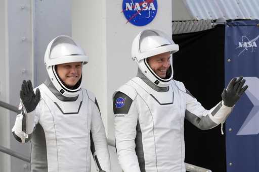 Roscosmos cosmonaut Aleksandr Gorbunov, left, and NASA astronaut Nick Hague wave as they leave the …