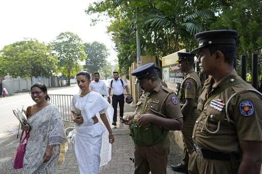 Women election officials walk past security personnel outside a distribution center before collecti…