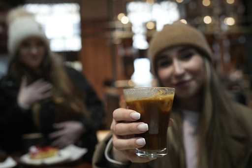 Kaya Cupial, right, shows her Oleato Iced Cortado coffee at the Starbucks coffee shop in Milan, Ita…