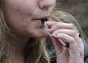 A high school student uses a vaping device near a school campus in Cambridge, Mass