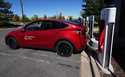 A Tesla Model 3 charges at a Tesla supercharging station situated in the parking lot of an outlet m…