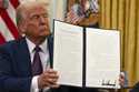 President Donald Trump holds up a signed executive order aiming to declassify remaining federal rec…