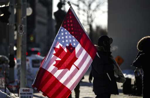 A protester holds the flags of Canada and the United States outside on Parliament Hill in Ottawa, o…