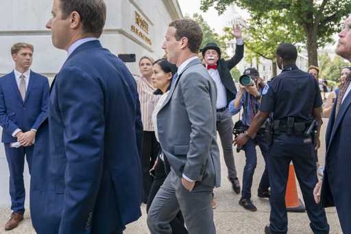 Meta CEO Mark Zuckerberg passes media and a protester as he arrives for a closed-door gathering of …