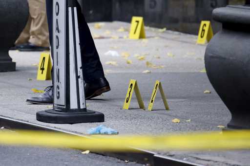 Members of the New York police crime scene unit investigate bullets lying on the sidewalk at the sc…