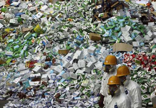 Workers prepare to destroy over 50 tons of confiscated fake medicine during a campaign to mark Worl…