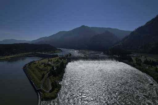 Water spills over the Bonneville Dam on the Columbia River, which runs along the Washington and Ore…