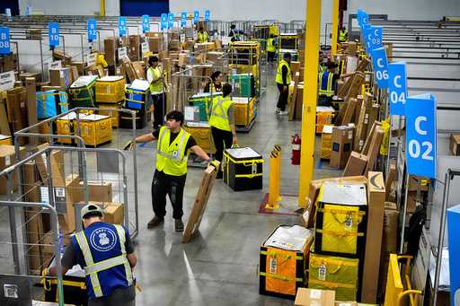 Amazon employees load packages on carts before being put on to trucks for distribution for Amazon's…