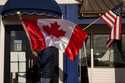 A worker at The Pier, one of three restaurants in town, readjusts Canadian and American flags hangi…